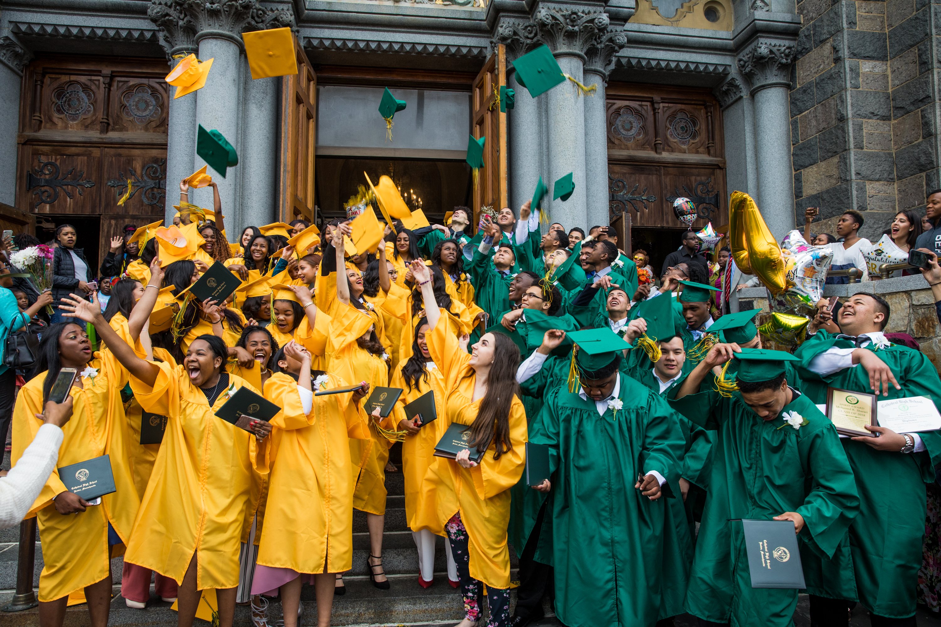 Graduates of the Class of 2018 toss their motarboards
