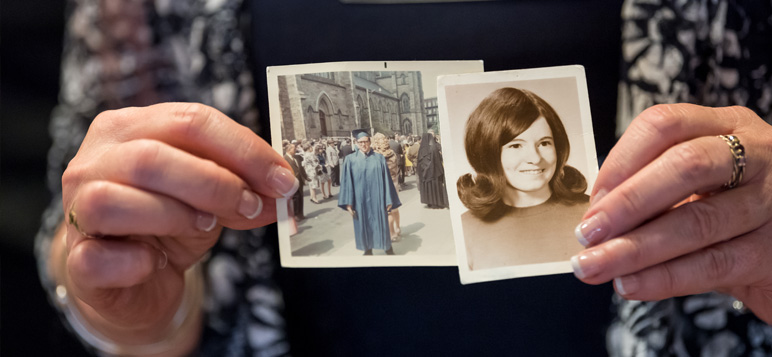 An Alumna holds Photographs from her Yearbook and Graduation from Cathedral High School